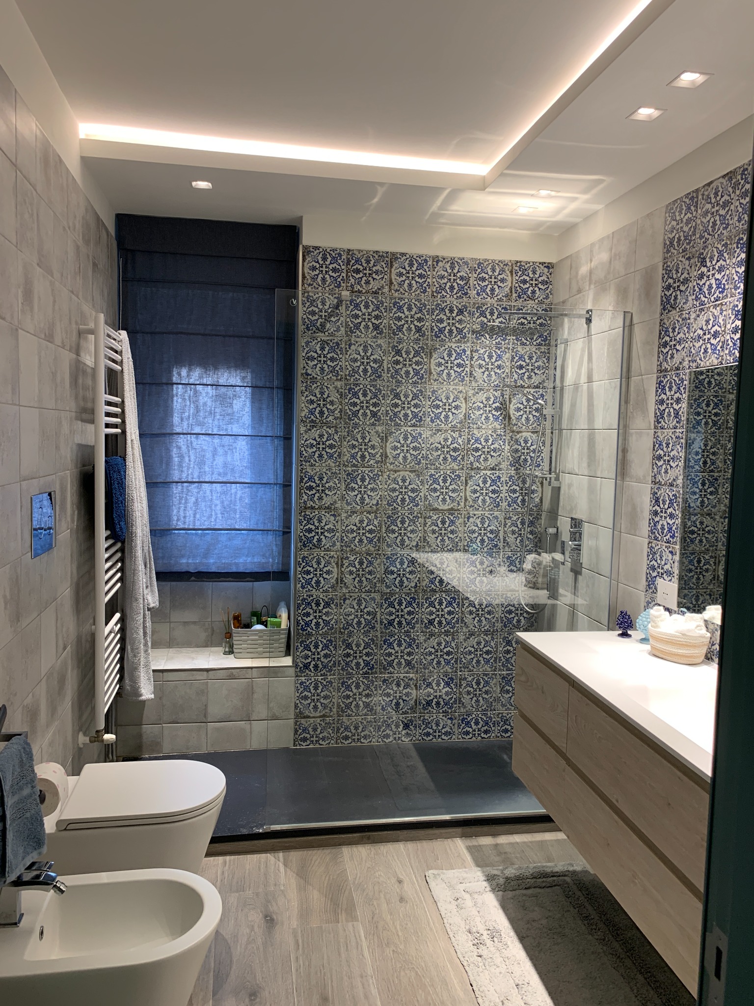 Bagno con rivestimenti decorati in blu e doccia in vetro