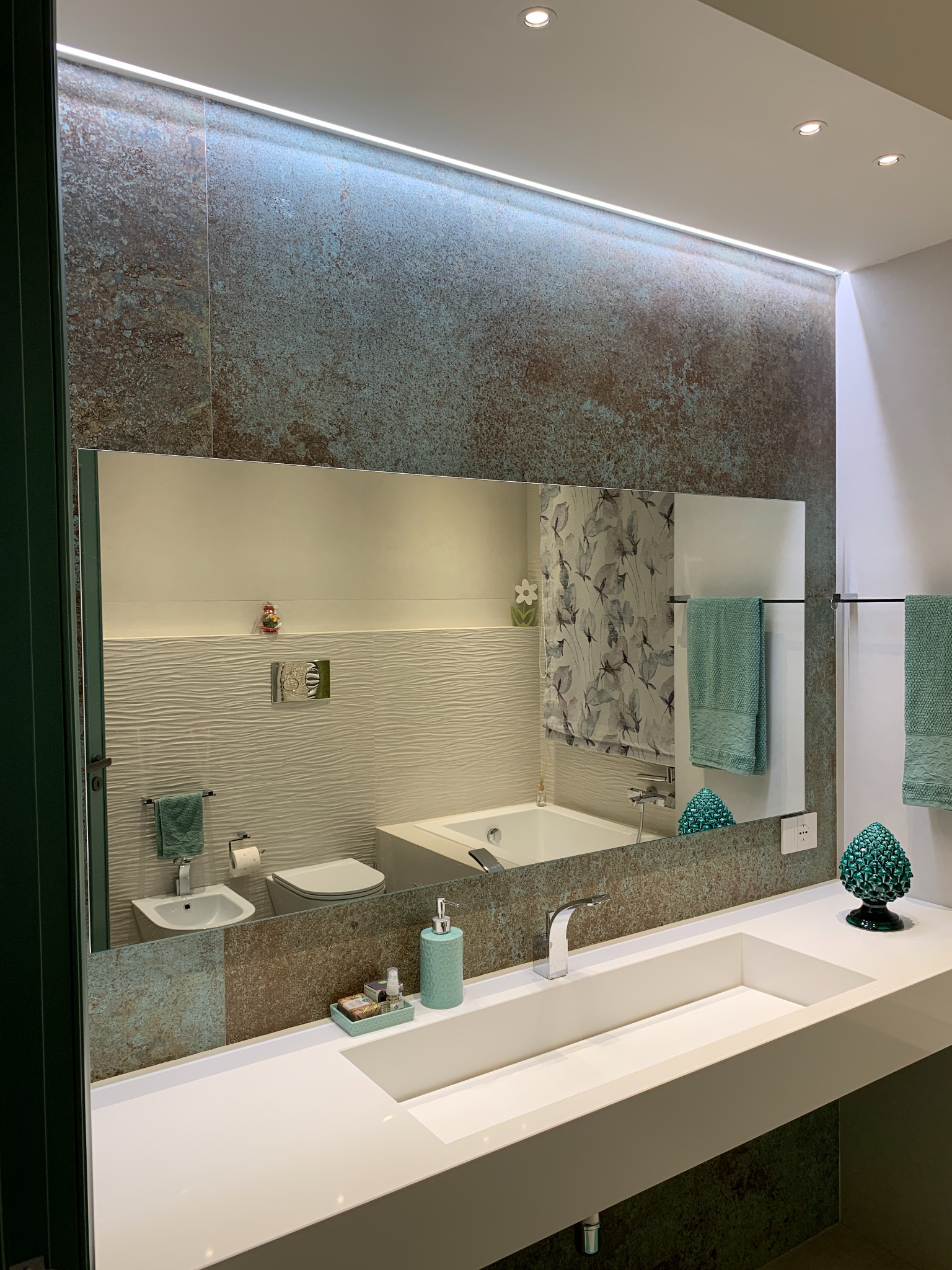 Bagno con lavabo sospeso e rivestimento nei toni del verde